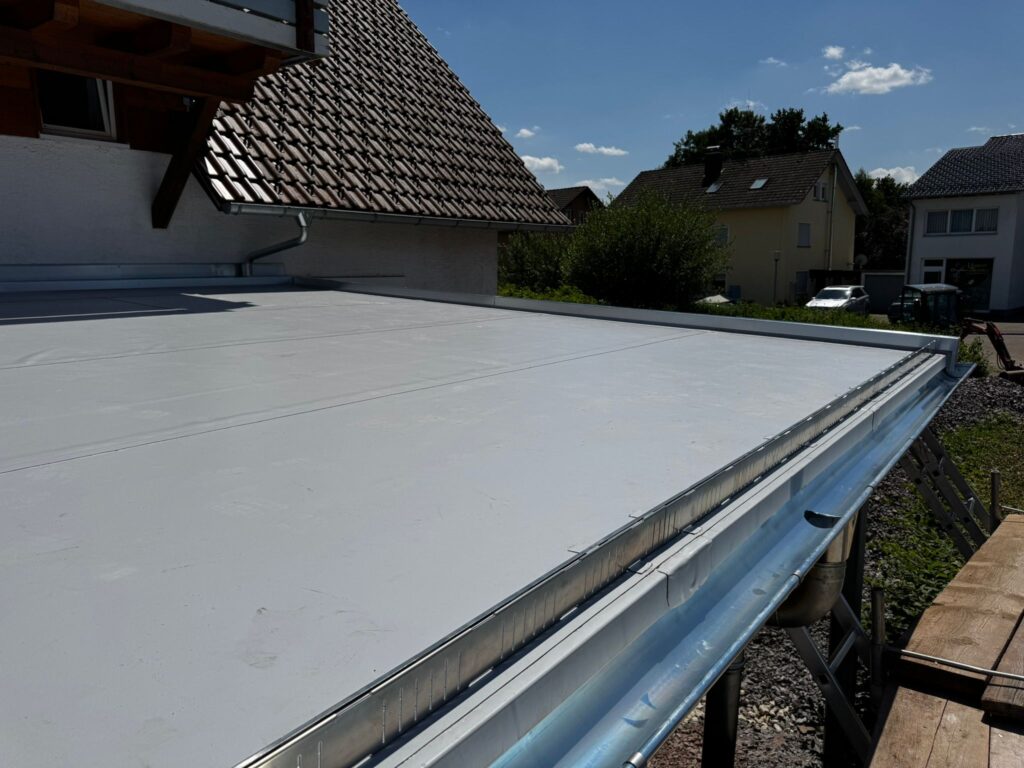 Flachdach mit neuer Kunststoffabdichtung und Dachrinne an einem Einfamilienhaus
